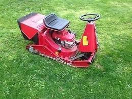 Compact red ride-on mower photographed on grass from an elevated angle.